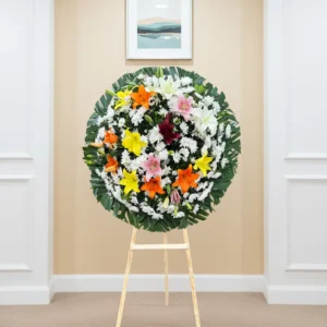 Pésame para un amigo con lirios de colores en arreglo floral de luto