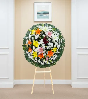 Pésame para un amigo con lirios de colores en arreglo floral de luto